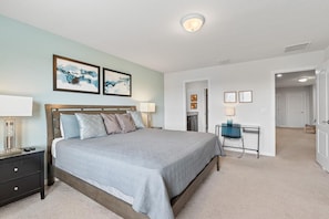 A bedroom with a bed, bedside tables, a desk, and a chair. There are two framed pictures on the wall. - 5-bedroom Villa With Private Pool Near Disney (Kissimmee)