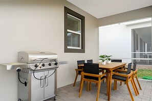 A patio with a grill, a table with chairs, and a window with blinds. - Luxury 6bd/5.5ba Brand new Home Game Room (Davenport)