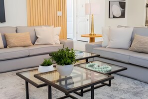 A modern living room with two grey sofas, a glass coffee table, and a small side table with a lamp. - Luxury 6bd/5.5ba Brand new Home Game Room (Davenport)