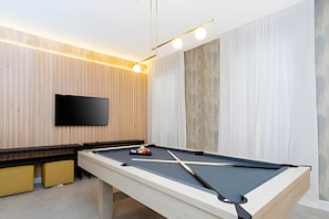 A pool table with a mounted television above it, wooden panel walls, and a modern light fixture. - Luxury 6bd/5.5ba Brand new Home Game Room (Davenport)
