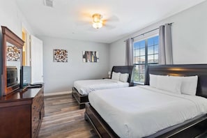 A hotel room with two beds, a dresser, a television, and artwork on the walls. - Elegant 4BR Vista Cay Resort (Orlando)