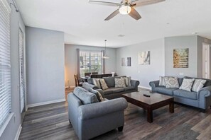 A living room with a ceiling fan, two sofas, a coffee table, and a dining area in the background. - Elegant 4BR Vista Cay Resort (Orlando)