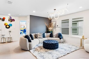 Ein modernes Wohnzimmer mit einem Ecksofa, einem runden Hocker und einer Neonreklame.