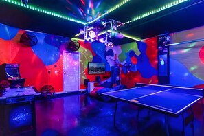 A room with a ping pong table, a TV, and a wall with abstract art. - Luxury 5BR Villa Near Disney w/ Lazy River Access (Davenport)