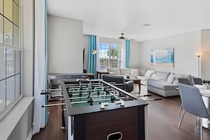 A modern living room with a foosball table, a sofa, and a coffee table. - Vista Cay 4BR Condo w/ Balcony & Foosball Fun (Orlando)