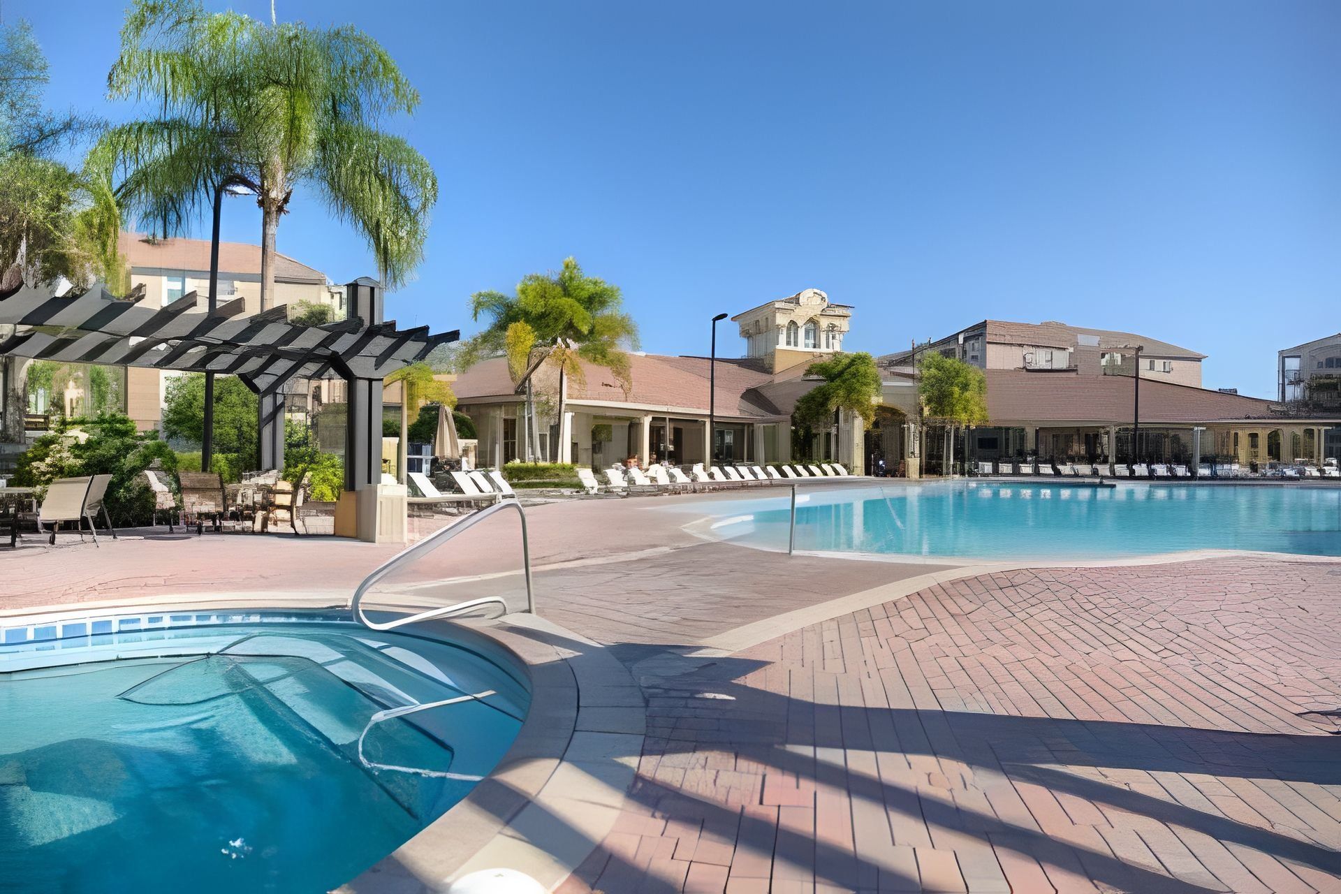 A swimming pool with lounge chairs and a covered seating area.