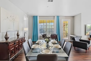 A dining area with a rectangular table set for four, surrounded by chairs. - Vista Cay 4BR Condo w/ Balcony & Foosball Fun (Orlando)