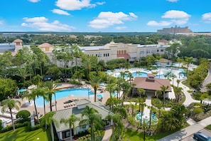A resort with multiple swimming pools, lush greenery, and a large building in the background. - Vista Cay 4BR Condo w/ Balcony & Foosball Fun (Orlando)