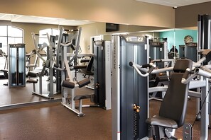 Une salle de sport équipée de divers appareils d’entraînement, notamment des appareils de musculation et des poids libres.