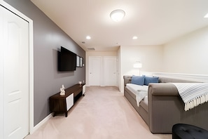 A bedroom with a bed, a bedside table, a TV mounted on the wall, and a door. - Windsor 5BR Villa w/ Pool Near Disney (Kissimmee)