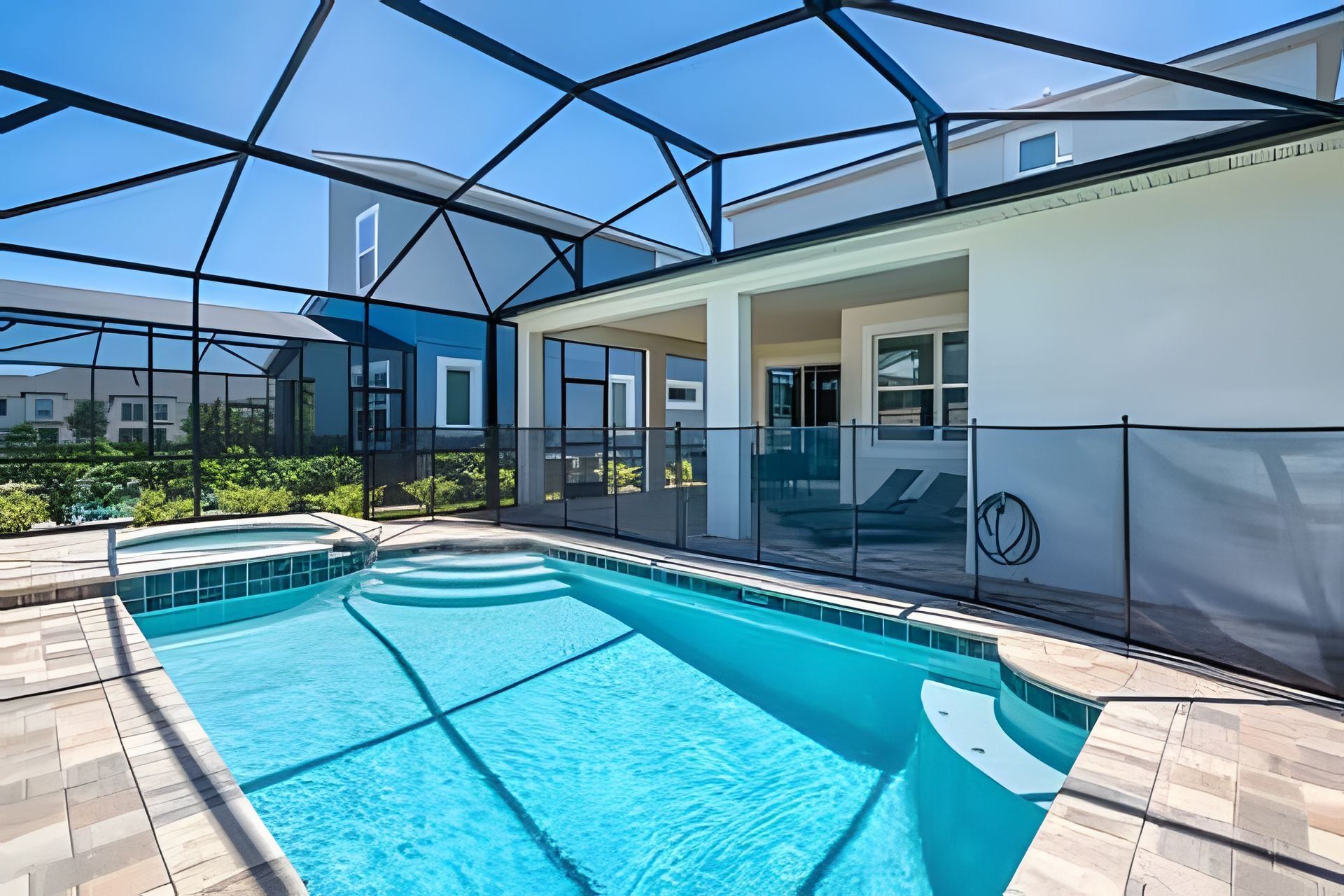 A modern indoor swimming pool with a glass ceiling, surrounded by a covered patio area.