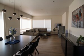 A modern living room with a dining area, a sofa, a coffee table, and a painting on the wall. - A 5-star single-story vacation home with all the comforts and a large garden. (Poperinge)