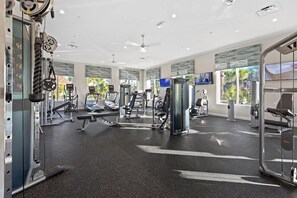 Une salle de sport moderne dotée de divers équipements d’exercice, de grandes fenêtres et d’un intérieur propre et bien éclairé.