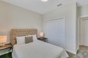 A neatly arranged bedroom with a large bed, a bedside table with a lamp, and a wardrobe. - Storey Lake 6BR Home w/ Pool & Game Room (Kissimmee)