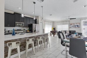 A modern kitchen with dark cabinets, a white countertop, and a central island with bar stools.