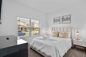 A bedroom with a bed, bedside tables, a window with blinds, and artwork on the wall. - 5BR Townhome w/ Pool at Champions Gate (Davenport)