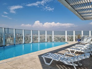 Ein Pool auf dem Dach mit freiem Blick auf Stadt und Berge.