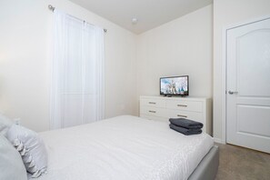 Un dormitorio con una cama, un aparador, un televisor y una puerta.