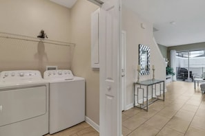 A laundry room with two washing machines, a drying rack, and a small table with a mirror. - 5BR Storey Lake Home, Sleeps 13 (Kissimmee)