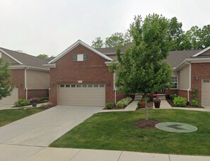 A two-story brick house with a garage, a well-maintained lawn, and a small tree in the front yard. - Cozy 1-bedroom house in peaceful Auburn Hills with AC (Auburn Hills)