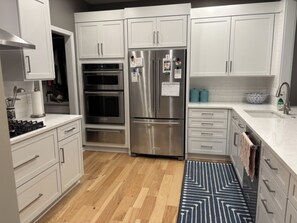 A modern kitchen with stainless steel appliances, white cabinetry, and a wooden floor. - Cozy 1-bedroom house in peaceful Auburn Hills with AC (Auburn Hills)