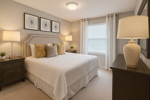 A bedroom with a large bed, two bedside tables, a nightstand, a lamp, and a mirror. - Luxury 6BR Villa w/ Private Pool at Solterra (Davenport)