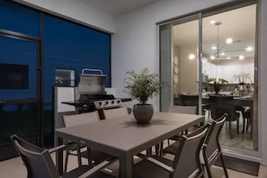 A dining area with a table and chairs, a grill, and a potted plant. - Luxury 6-bedroom Retreat w/ Heatable Pool (Kissimmee)