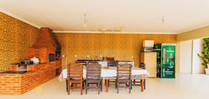 A dining area with a brick wall, a brick oven, and a Heineken refrigerator. - Casa em Braganca Paulista com Piscina (Bragança Paulista)