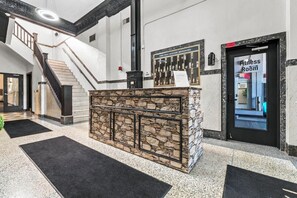 A reception area with a stone counter, a staircase, and a door labeled 'Fitness Room'. - Downtown Cleveland 1BR | Walk to Playhouse Square (Cleveland)