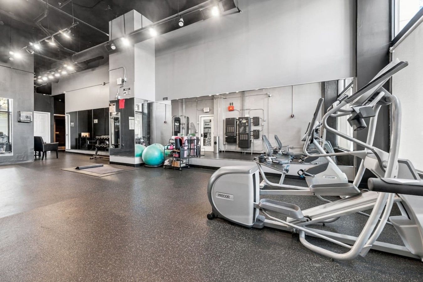 Ein Fitnessstudio mit Trainingsgeräten, einem großen Spiegel und einem Bereich zum Gewichtheben.