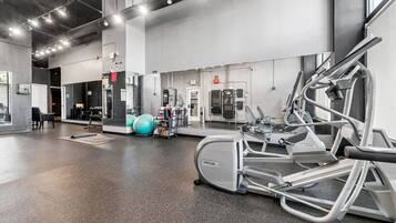Ein Fitnessstudio mit Trainingsgeräten, einem großen Spiegel und einem Bereich zum Gewichtheben.
