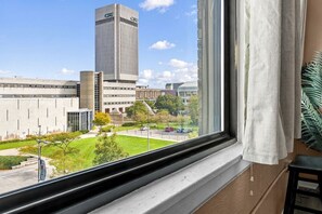 Vista desde una ventana de un complejo de edificios con una estructura alta con la etiqueta 'CSU' y un área de estacionamiento.