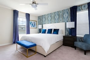A modern bedroom with a large bed, a bedside table, a bench, and a chair. - 6BR Disney Retreat w/ Pool & Themed Rooms (Davenport)