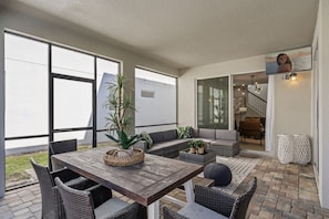 An outdoor patio with a wooden table, wicker chairs, and a seating area with cushions. - 6br/5ba Luxurious With Private Pool (Kissimmee)