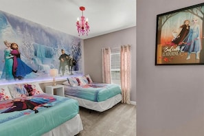 A bedroom with two beds, a mural of animated characters, a chandelier, and a framed poster on the wall. - 5BR Storey Lake Townhome, Heated Pool (Kissimmee)