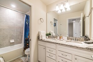 A bathroom with a bathtub, toilet, and a large mirror. There are towels and toiletries on the counter. - 5b/4.5b Pool and Resort (Davenport)