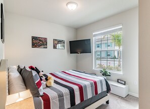 A bedroom with a bed, a TV mounted on the wall, and a window with a view of the outside. - 5b/4.5b Pool and Resort (Davenport)