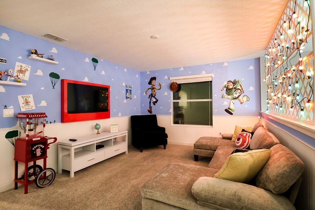 A room with a TV, a black chair, a red popcorn cart, and a window with a view of a dog.