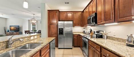 A modern kitchen with granite countertops, stainless steel appliances, and wooden cabinets.