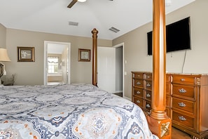 A bedroom with a large bed, a wooden dresser, a ceiling fan, and a television on the wall. - Family 6BR Villa w/ Marvel Game Room & Pool (Kissimmee)