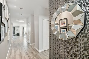 A hallway with a modern geometric wall art piece and a patterned wallpaper. - 6BR Storey Lake Home, Private Pool (Kissimmee)