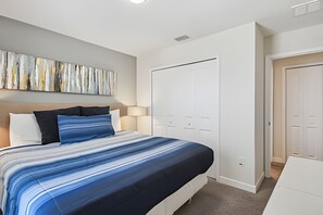 A bedroom with a bed, a nightstand, a lamp, a wardrobe, and a painting on the wall. - 6BR Storey Lake Home, Private Pool (Kissimmee)