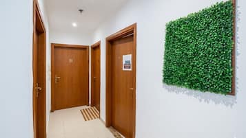 Een gang met houten deuren, een betegelde vloer en een groene wanddecoratie.