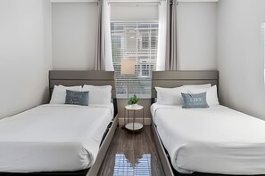 A hotel room with two beds, a small table with a plant, and a window with a city view. - Modern 4BR Resort Townhome Near Universal (Orlando)