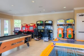 Une salle avec une table de billard, des jeux d’arcade et une table de ping-pong.