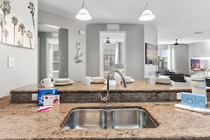 A modern kitchen with granite countertops, stainless steel sink, and pendant lighting. - Modern 4BR Resort Townhome Near Universal (Orlando)