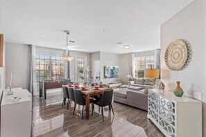 A modern living room with a dining area, a sofa, a coffee table, and a TV. - Modern 3-bedroom Escape at Vista Cay (Orlando)