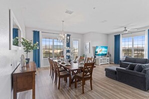 A spacious living room with a dining area, a grey sofa, and a TV. - Spacious 4BR Condo at Vista Cay Resort (Orlando)