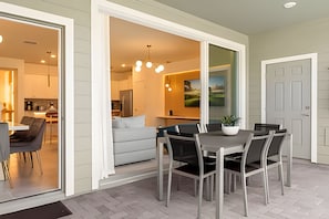 A dining area with a table and chairs, a kitchen in the background, and a door to the right. - Disney 5BR Resort Home + Lazy River & Mini Golf (Davenport)