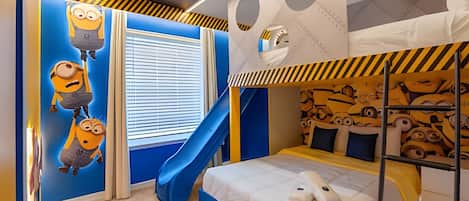 Een kinderkamer met een stapelbed, een glijbaan en Minion-decoraties.